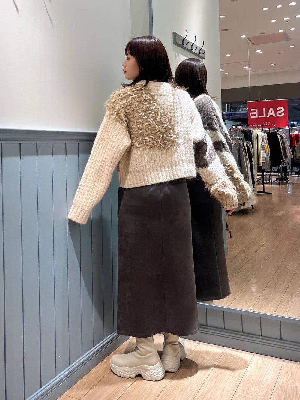 ホワイト系のブーツ、ブラック系のショルダーバッグ、グレー系のスカートを着用したレディースの冬コーディネートの7枚目の写真