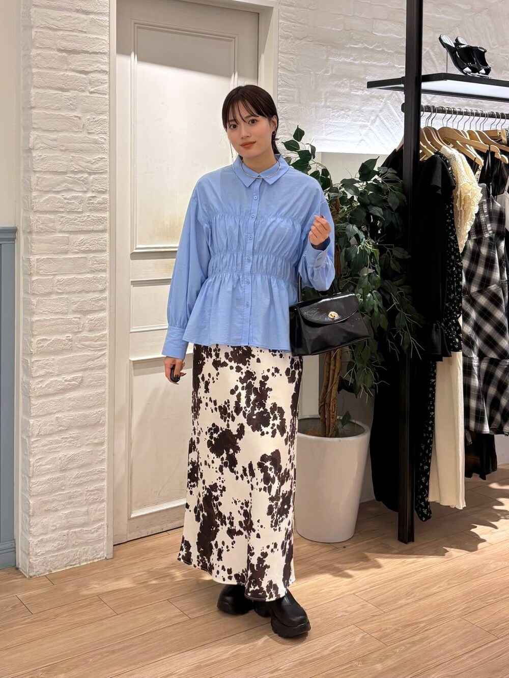 ブラック系のブーツ、その他のスカート、ブラック系のボストンバッグを着用したレディースの秋コーディネートの2枚目の写真