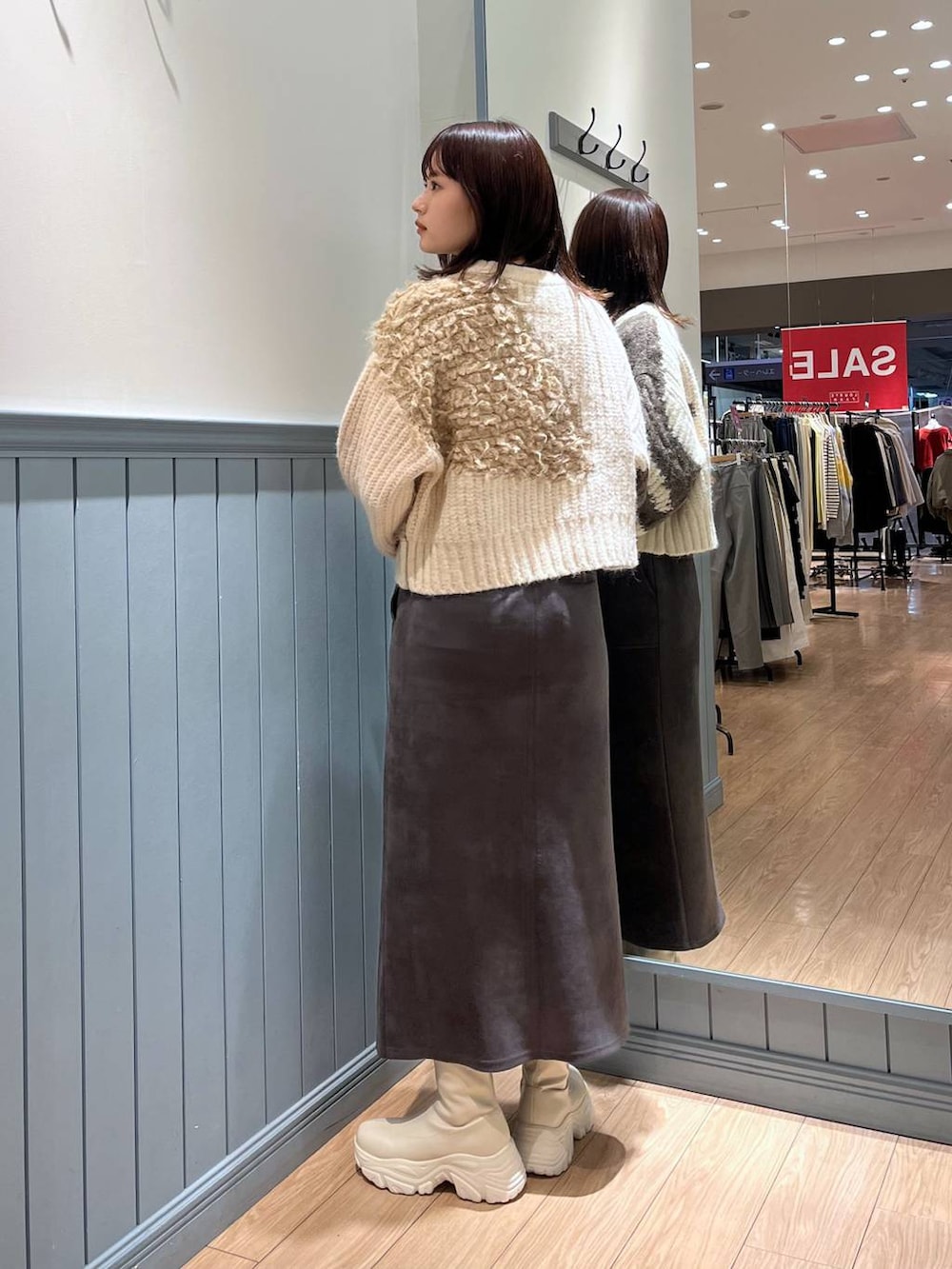 ホワイト系のブーツ、ブラック系のショルダーバッグ、グレー系のスカートを着用したレディースの冬コーディネートの6枚目の写真