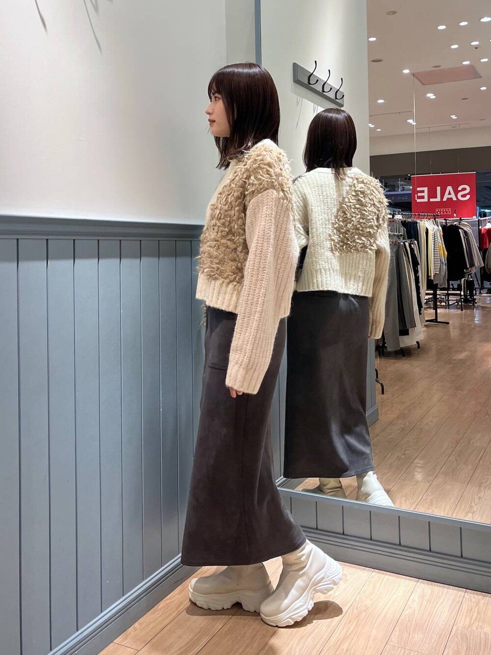 ホワイト系のブーツ、ブラック系のショルダーバッグ、グレー系のスカートを着用したレディースの冬コーディネートの5枚目の写真