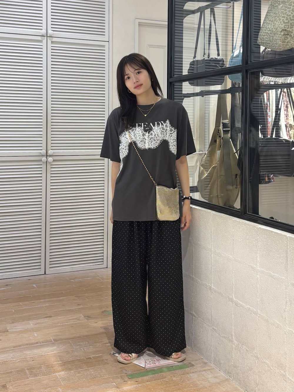 ゴールド系のショルダーバッグ、グレー系のTシャツ/カットソー、ホワイト系のサンダルを着用したレディースの夏コーディネートの2枚目の写真