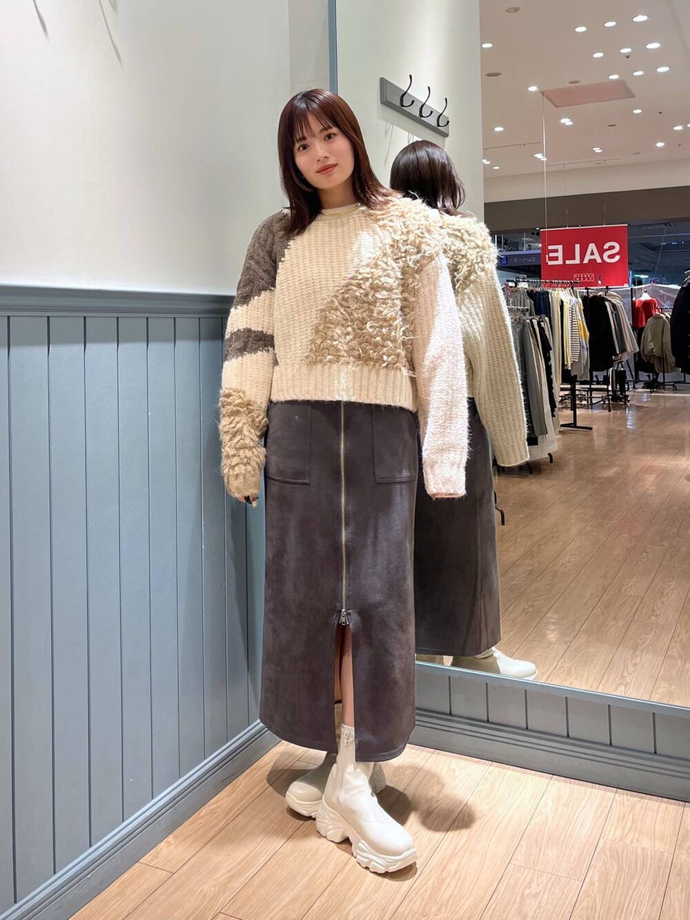 ホワイト系のブーツ、ブラック系のショルダーバッグ、グレー系のスカートを着用したレディースの冬コーディネートの8枚目の写真