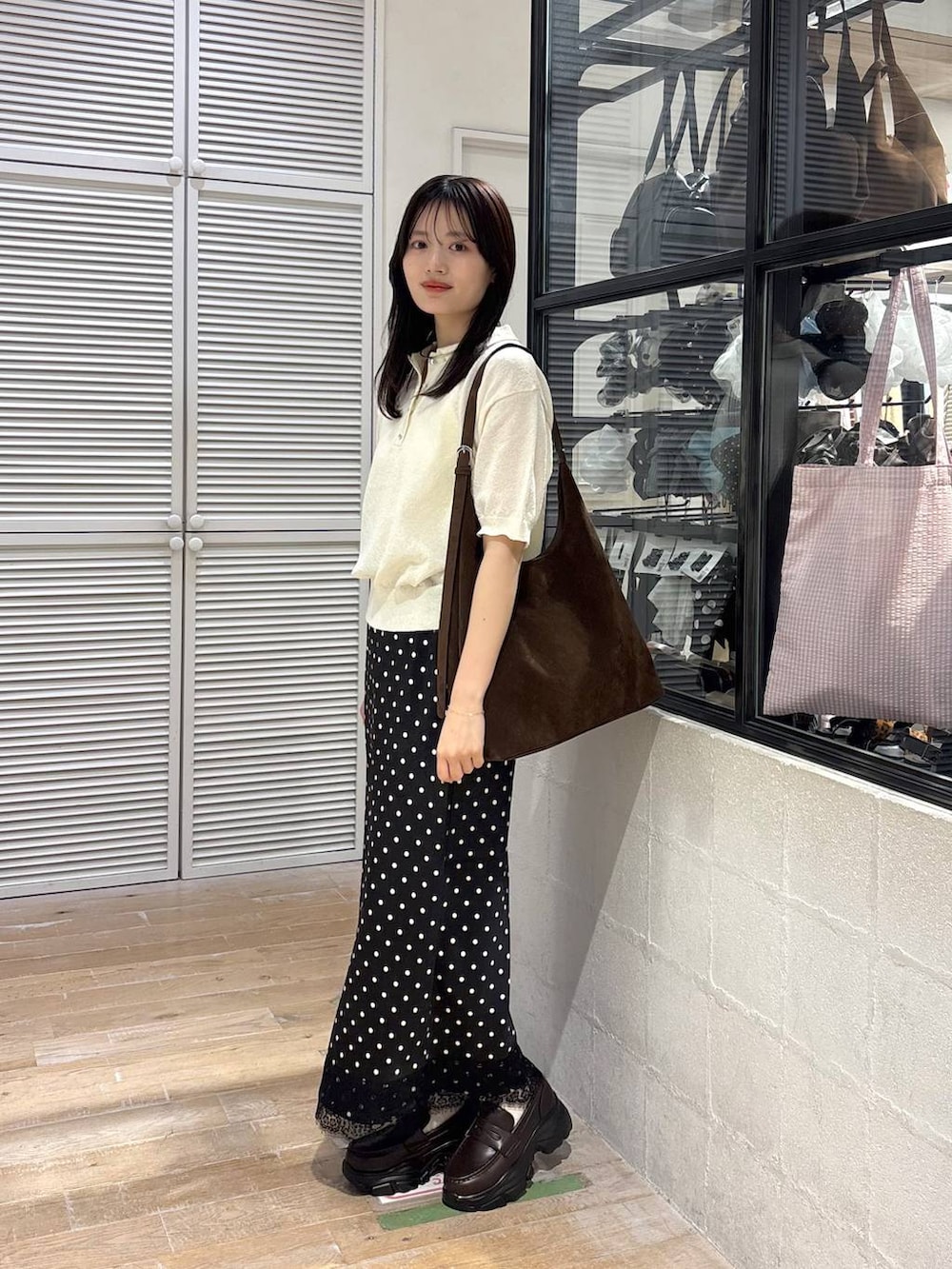 ブラウン系のショルダーバッグ、ブラウン系のローファー、ホワイト系のTシャツ/カットソーを着用したレディースの春コーディネートの6枚目の写真