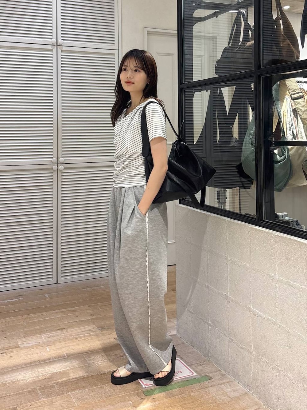 グレー系のスウェットパンツ、ホワイト系のサンダル、ホワイト系のTシャツ/カットソーを着用したレディースの春コーディネートの2枚目の写真