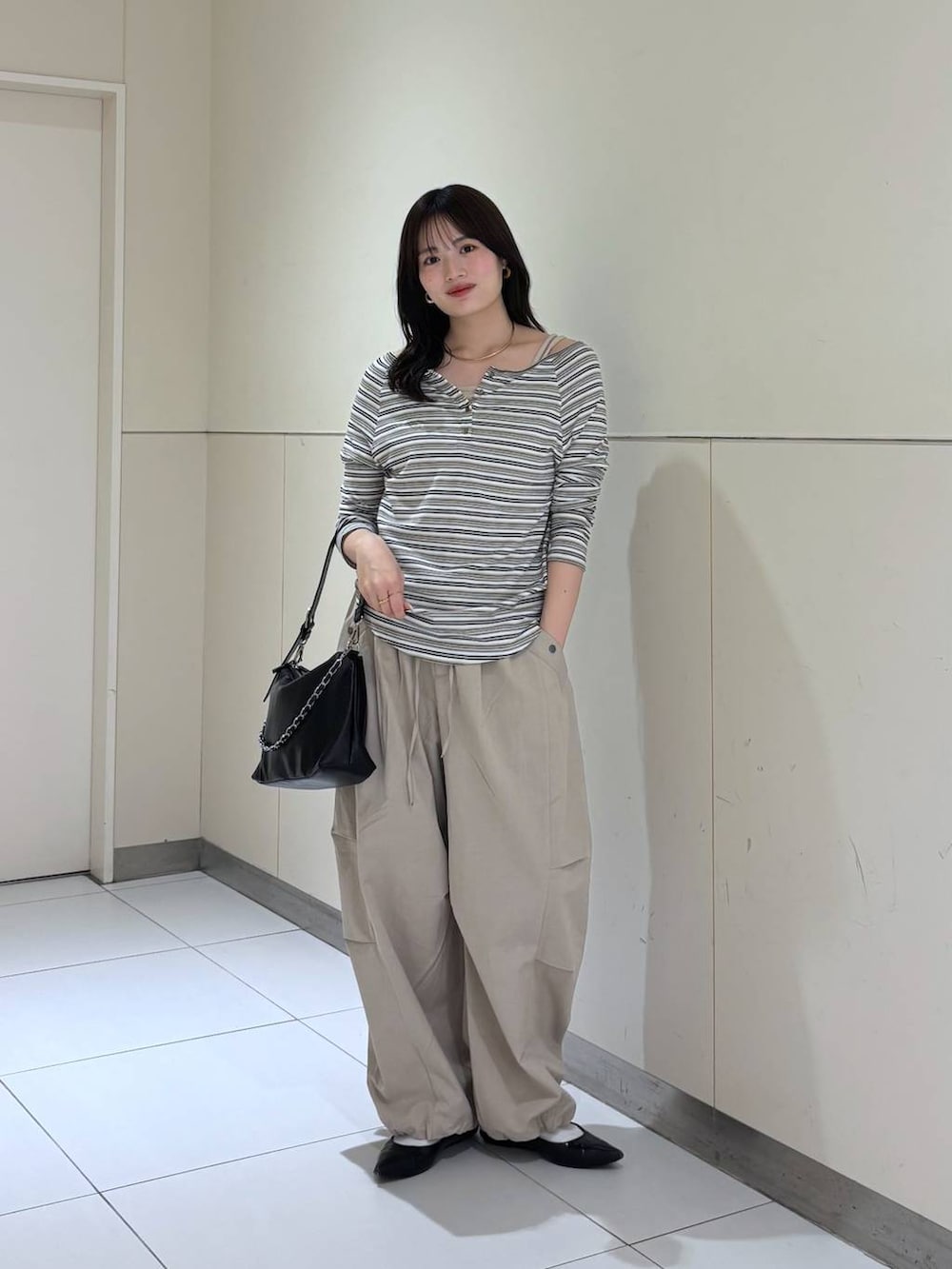 ホワイト系のTシャツ/カットソー、ブラック系のショルダーバッグ、ベージュ系のその他パンツを着用したレディースの春コーディネートの2枚目の写真