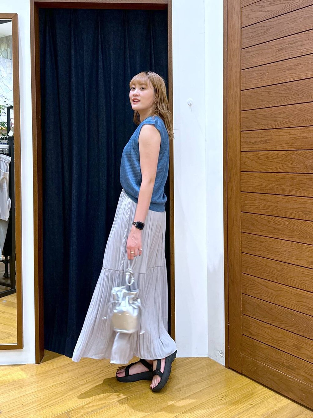 ブルー系のベスト、ブラック系のサンダル、グレー系のスカートを着用したレディースの夏コーディネートの2枚目の写真