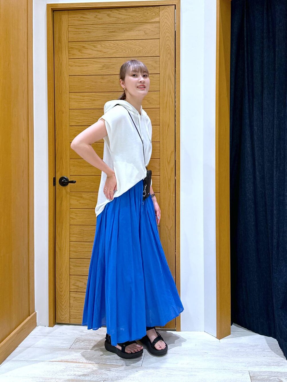 ブルー系のスカート、ホワイト系のTシャツ/カットソー、ブラック系のショルダーバッグを着用したレディースの夏コーディネートの2枚目の写真
