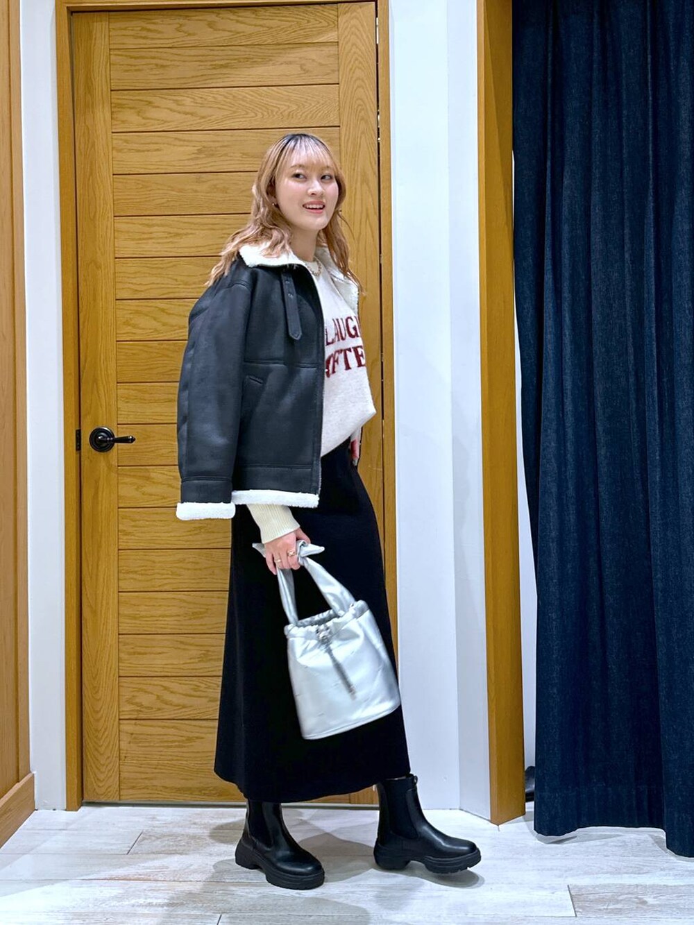 ブラック系のスカート、ブラック系のブーツ、シルバー系のショルダーバッグを着用したレディースの冬コーディネートの2枚目の写真