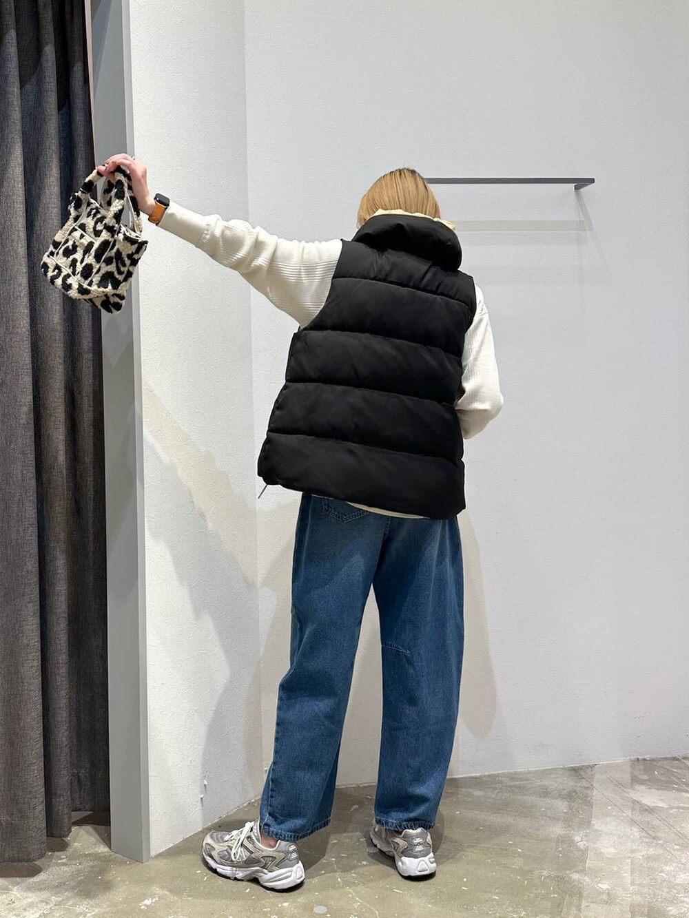 ベージュ系のトートバッグ、ブラック系のベスト、ホワイト系のTシャツ/カットソーを着用したレディースの秋コーディネートの3枚目の写真