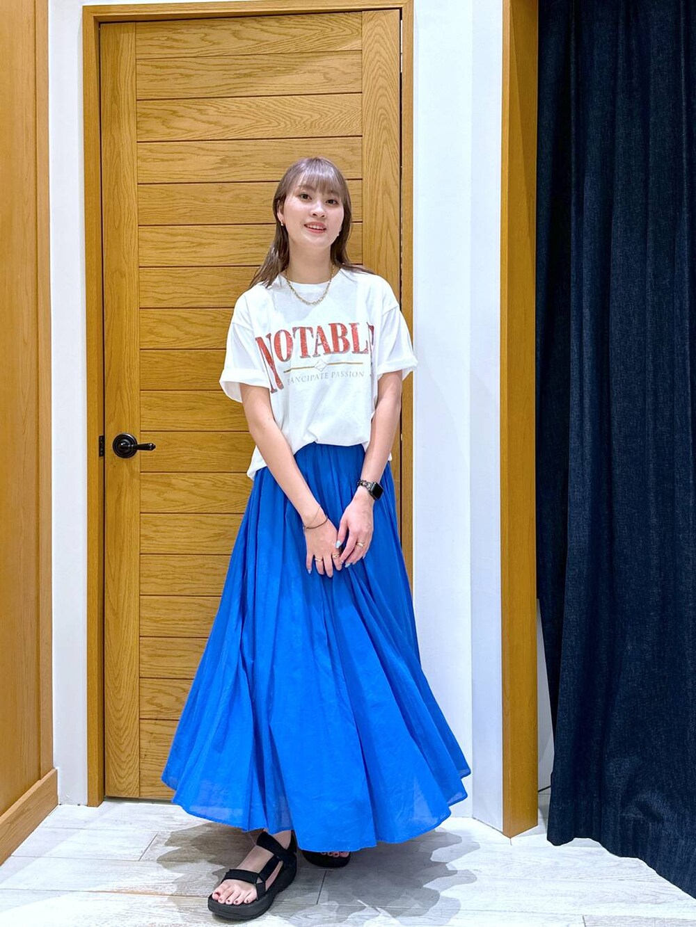 ブルー系のスカート、ブラック系のサンダル、ホワイト系のTシャツ/カットソーを着用したレディースの夏コーディネートの4枚目の写真