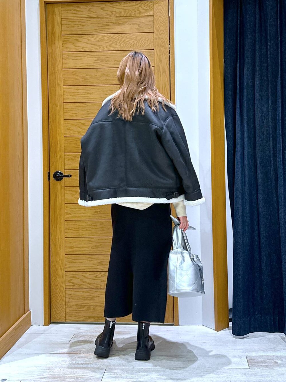 ブラック系のスカート、ブラック系のブーツ、シルバー系のショルダーバッグを着用したレディースの冬コーディネートの3枚目の写真