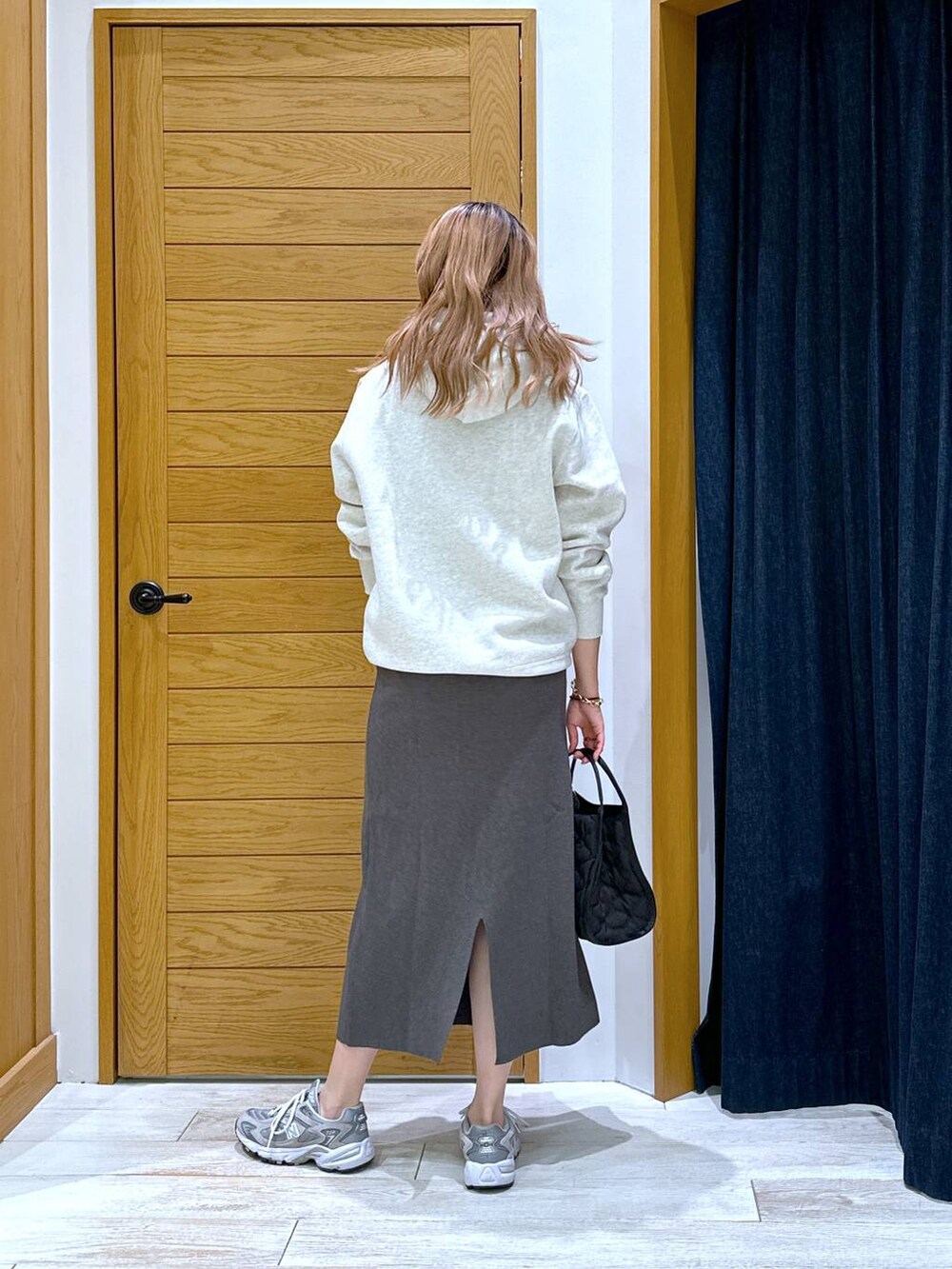 ベージュ系のパーカー、ブラック系のハンドバッグ、グレー系のワンピースを着用したレディースの秋コーディネートの3枚目の写真