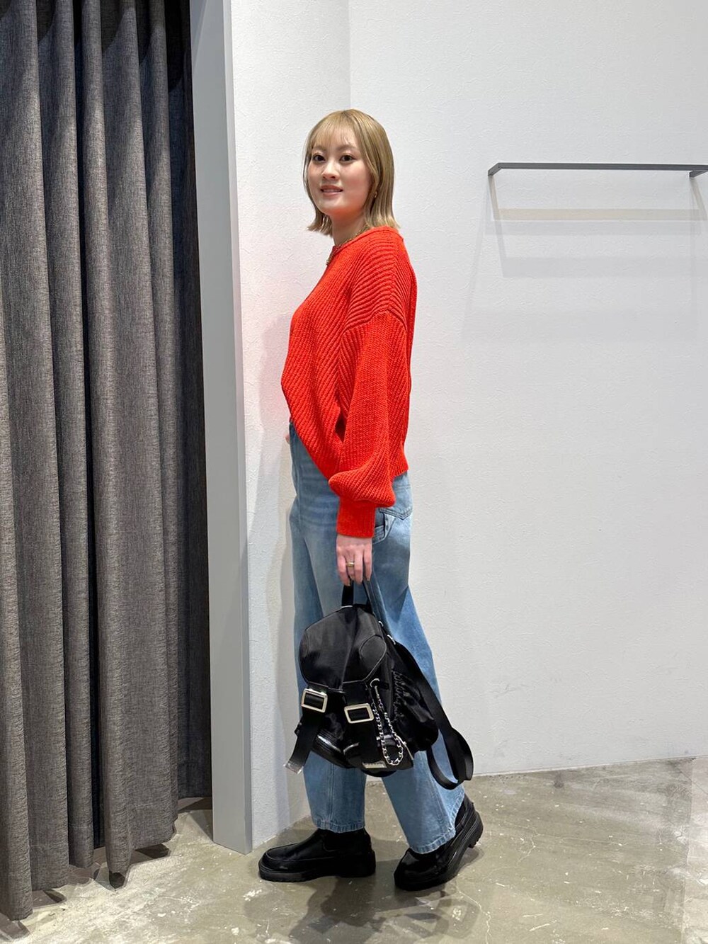 ブルー系のデニムパンツ、レッド系のニット/セーター、ブラック系のバックパック/リュックを着用したレディースの冬コーディネートの2枚目の写真