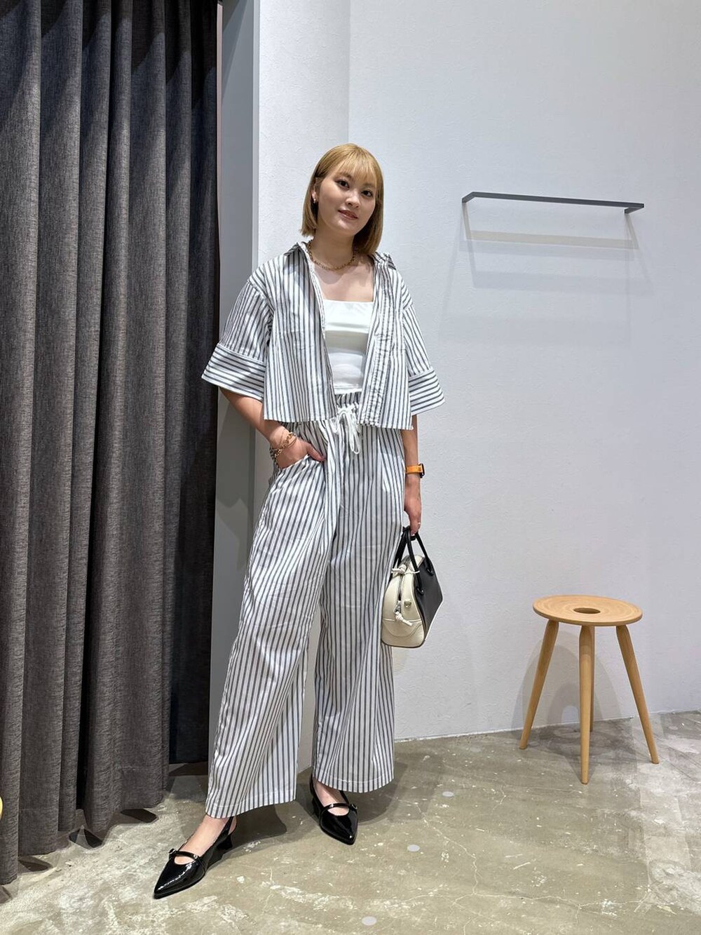 ブラック系のその他シューズ、ブラック系のハンドバッグ、ホワイト系のシャツ/ブラウスを着用したレディースの夏コーディネートの4枚目の写真