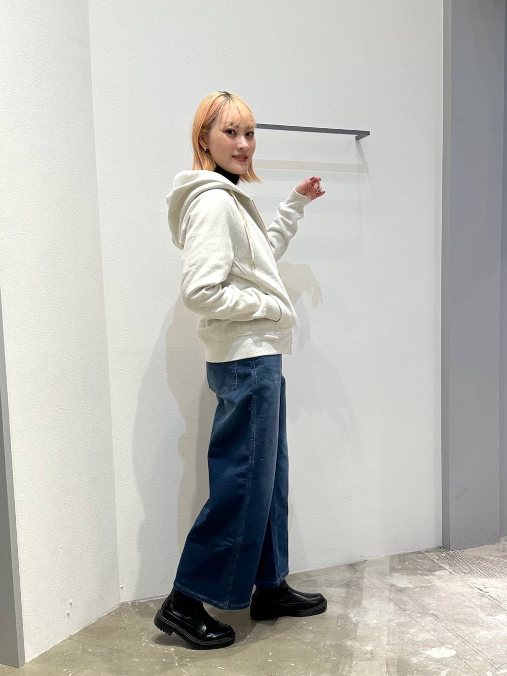 ブルー系のデニムパンツ、ホワイト系のパーカー、ブラック系のニット/セーターを着用したレディースの冬コーディネートの2枚目の写真