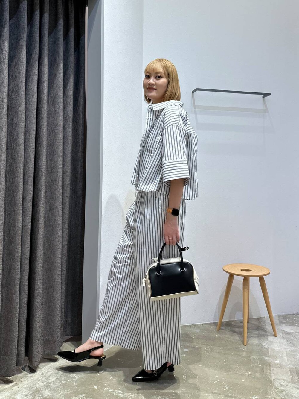 ブラック系のその他シューズ、ブラック系のハンドバッグ、ホワイト系のシャツ/ブラウスを着用したレディースの夏コーディネートの2枚目の写真