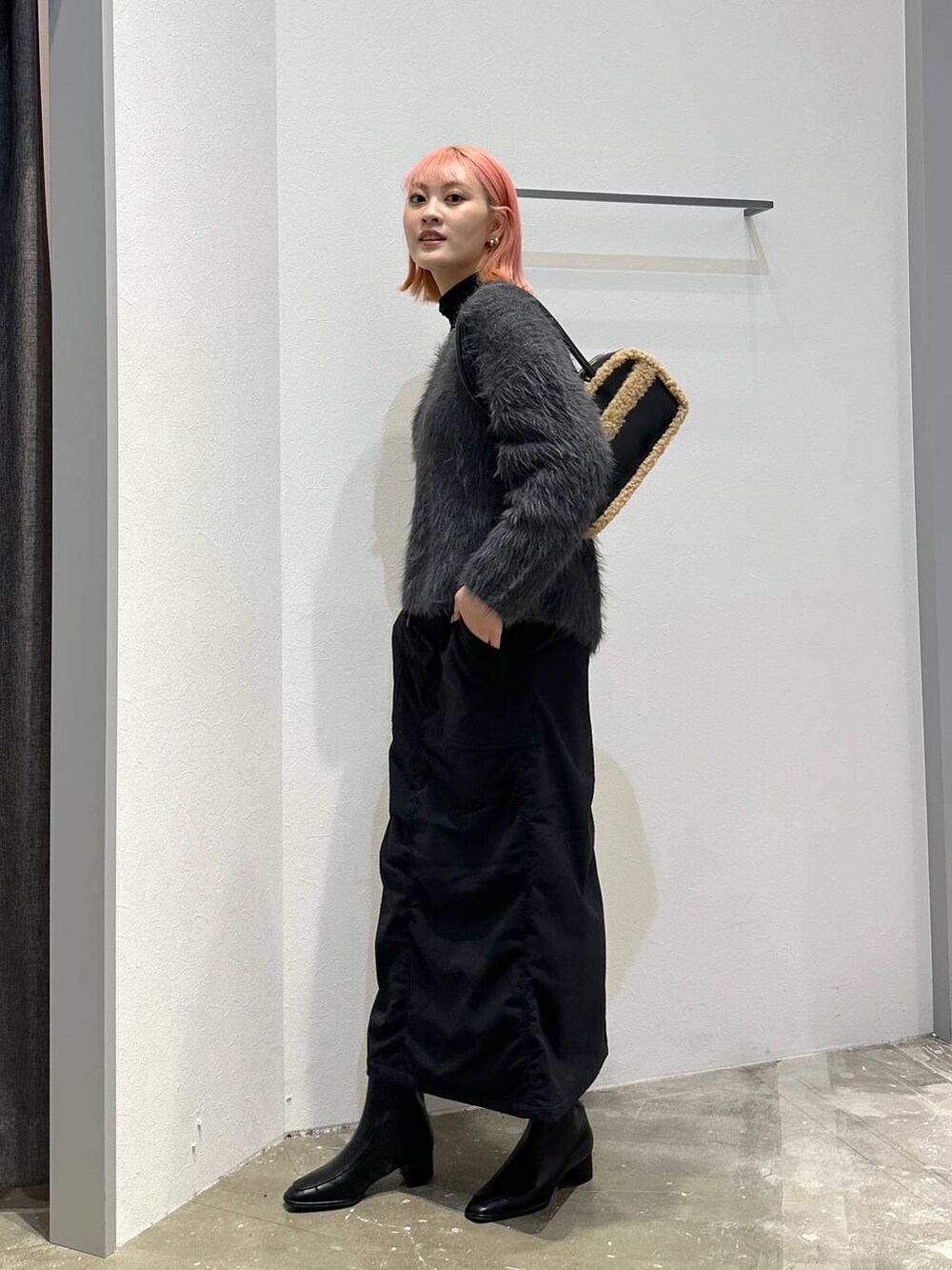 ブラック系のスカート、ブラック系のブーツ、ブラック系のTシャツ/カットソーを着用したレディースの秋コーディネートの2枚目の写真