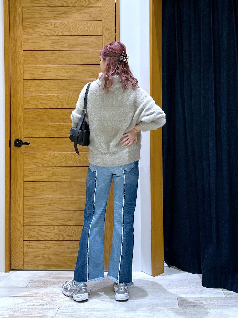 ブルー系のデニムパンツ、ブラック系のハンドバッグ、ベージュ系のニット/セーターを着用したレディースの秋コーディネートの3枚目の写真