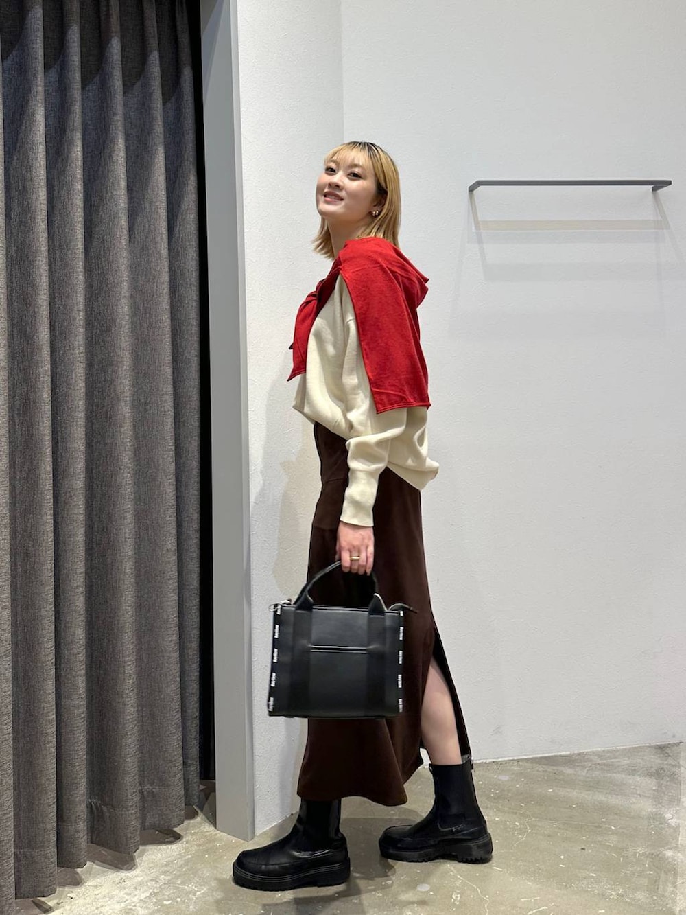 ブラウン系のスカート、ホワイト系のニット/セーター、ブラック系のトートバッグを着用したレディースの秋コーディネートの2枚目の写真