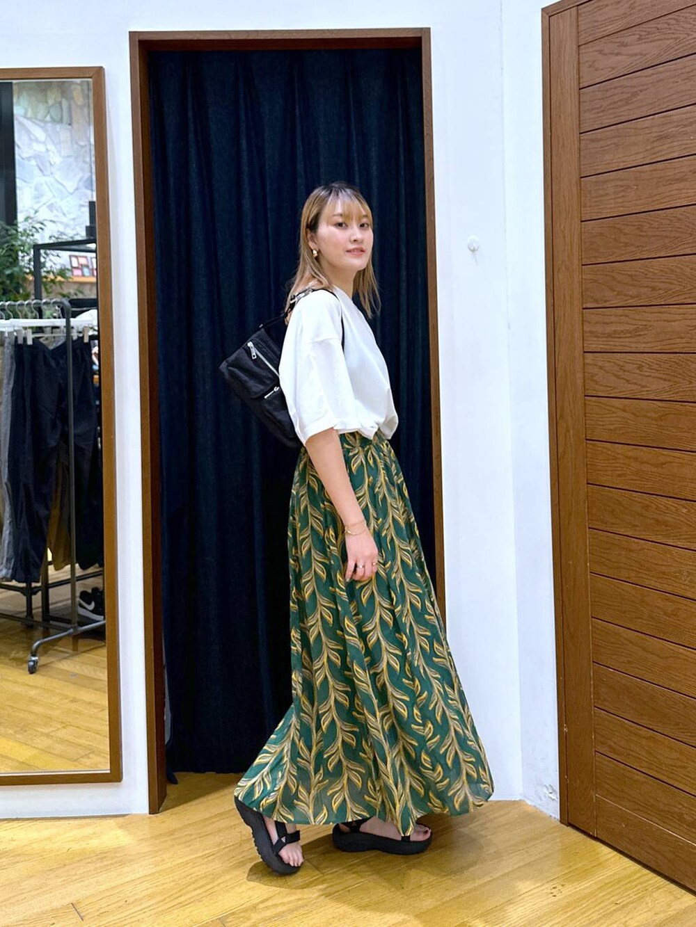 グリーン系のスカート、ブラック系のショルダーバッグ、ブラック系のサンダルを着用したレディースの夏コーディネートの2枚目の写真