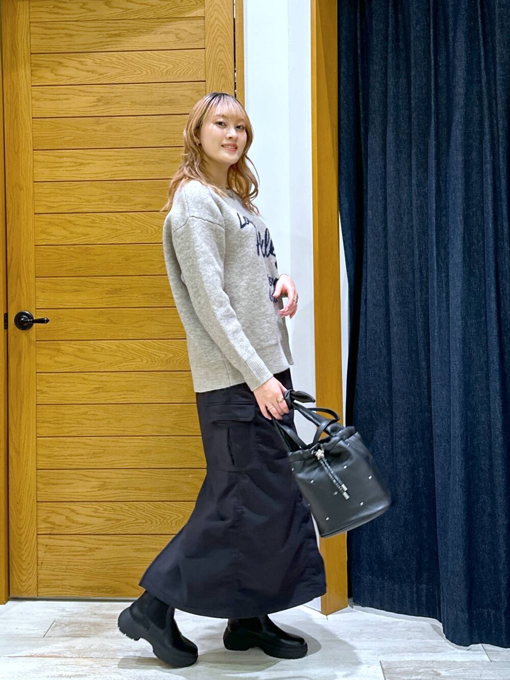 ブラック系のスカート、ブラック系のブーツ、ブラック系のショルダーバッグを着用したレディースの冬コーディネートの2枚目の写真