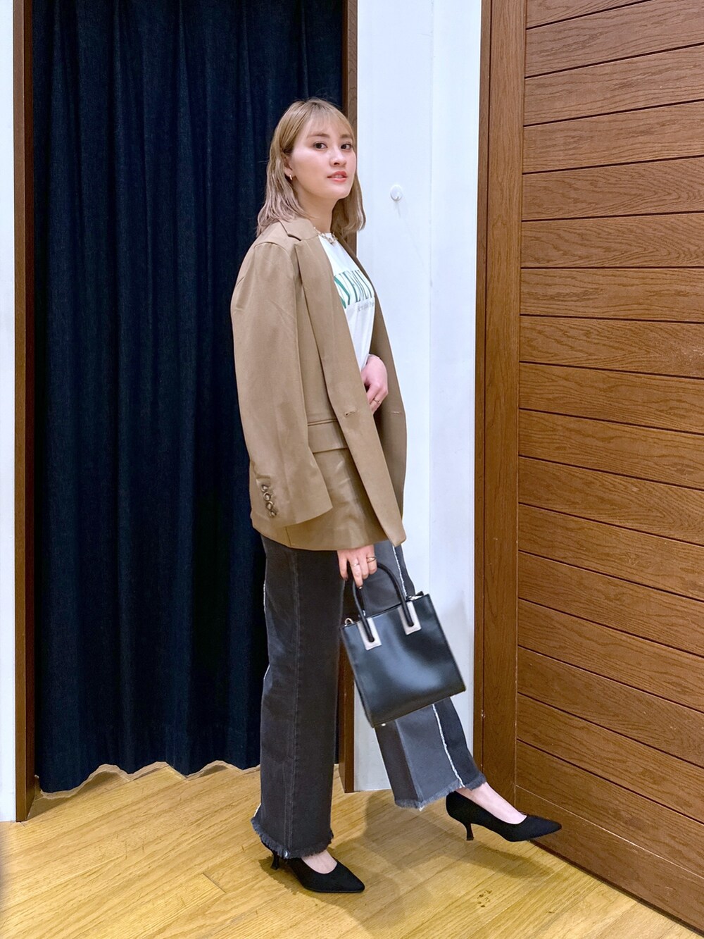 ブラック系のショルダーバッグ、ブラック系のデニムパンツ、ブラック系のパンプスを着用したレディースの冬コーディネートの2枚目の写真