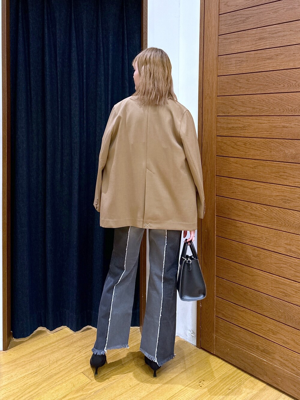 ブラック系のショルダーバッグ、ブラック系のデニムパンツ、ブラック系のパンプスを着用したレディースの冬コーディネートの3枚目の写真