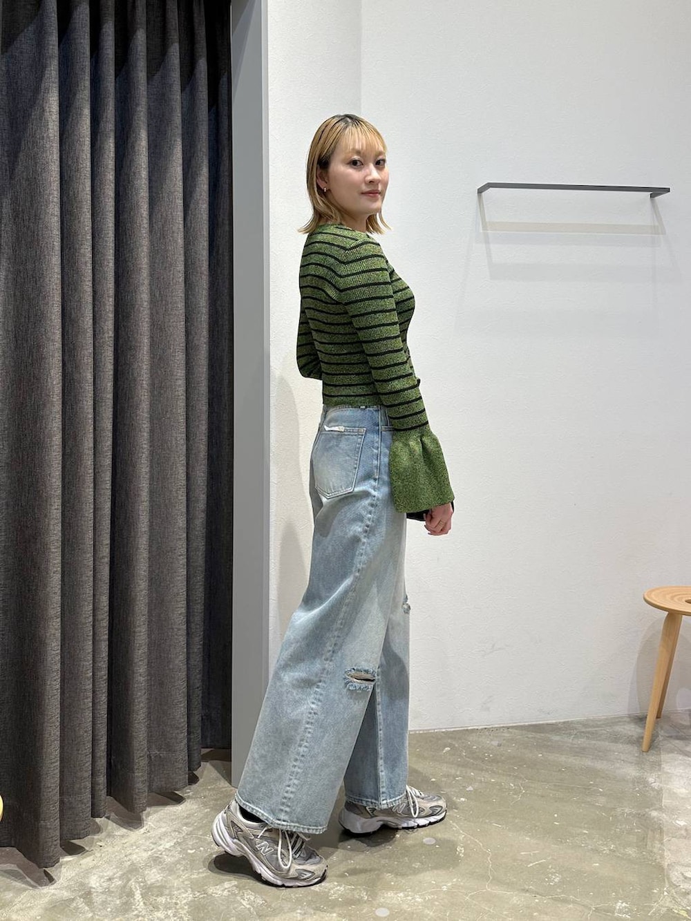 ブルー系のデニムパンツ、グリーン系のニット/セーター、ブラック系のベルトを着用したレディースの春コーディネートの3枚目の写真