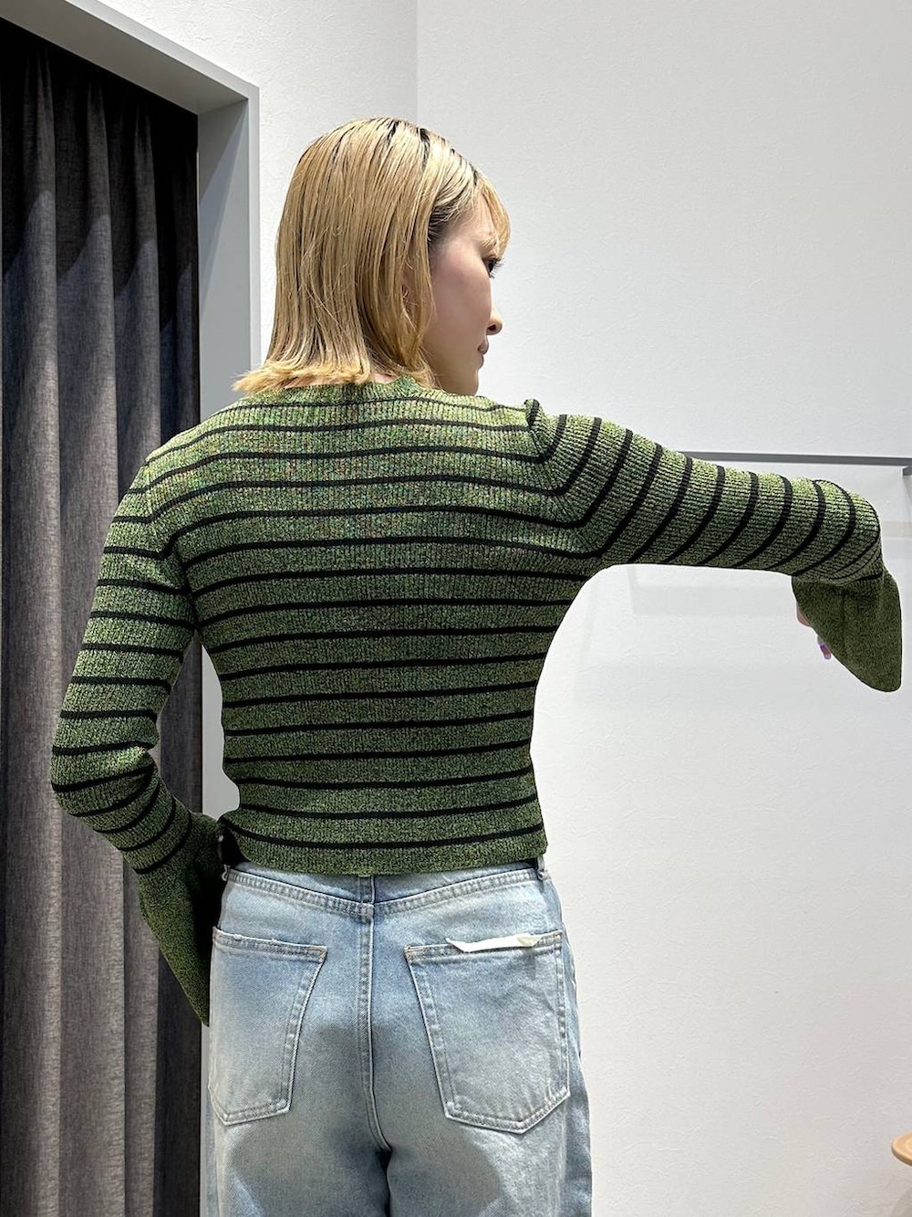 ブルー系のデニムパンツ、グリーン系のニット/セーター、ブラック系のベルトを着用したレディースの春コーディネートの6枚目の写真