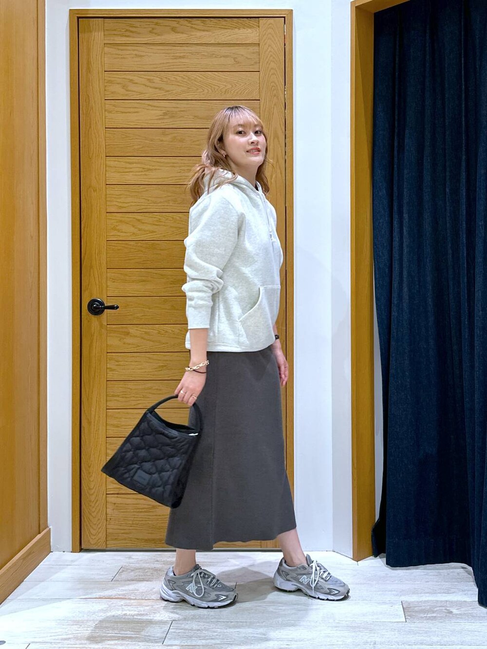 ベージュ系のパーカー、ブラック系のハンドバッグ、グレー系のワンピースを着用したレディースの秋コーディネートの2枚目の写真