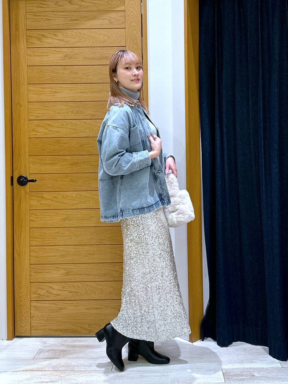 グレー系のニット/セーター、ブルー系のデニムジャケット、ブラック系のブーツを着用したレディースの秋コーディネートの2枚目の写真