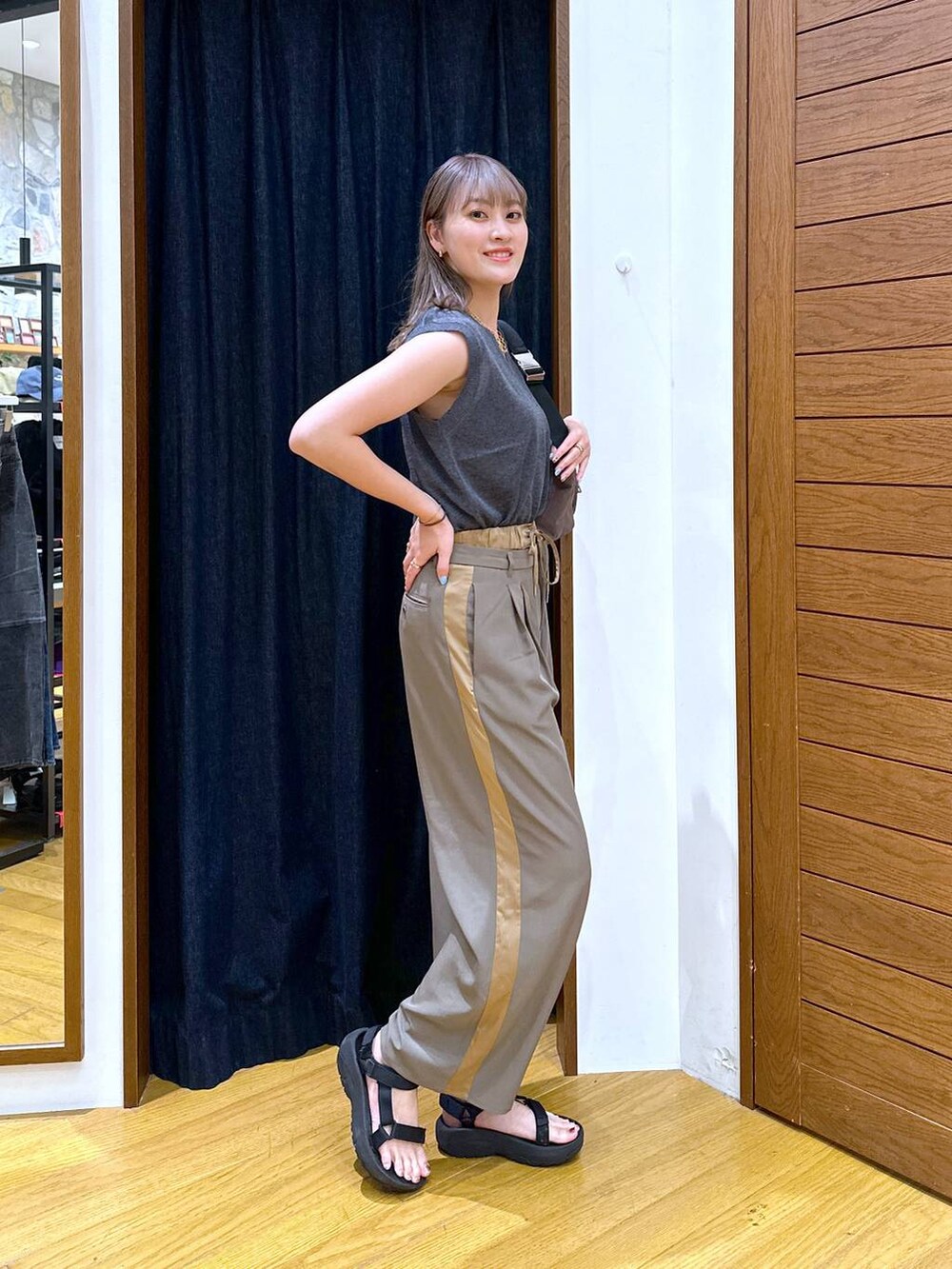 グリーン系のショルダーバッグ、ブラック系のベスト、ブラック系のサンダルを着用したレディースの秋コーディネートの2枚目の写真