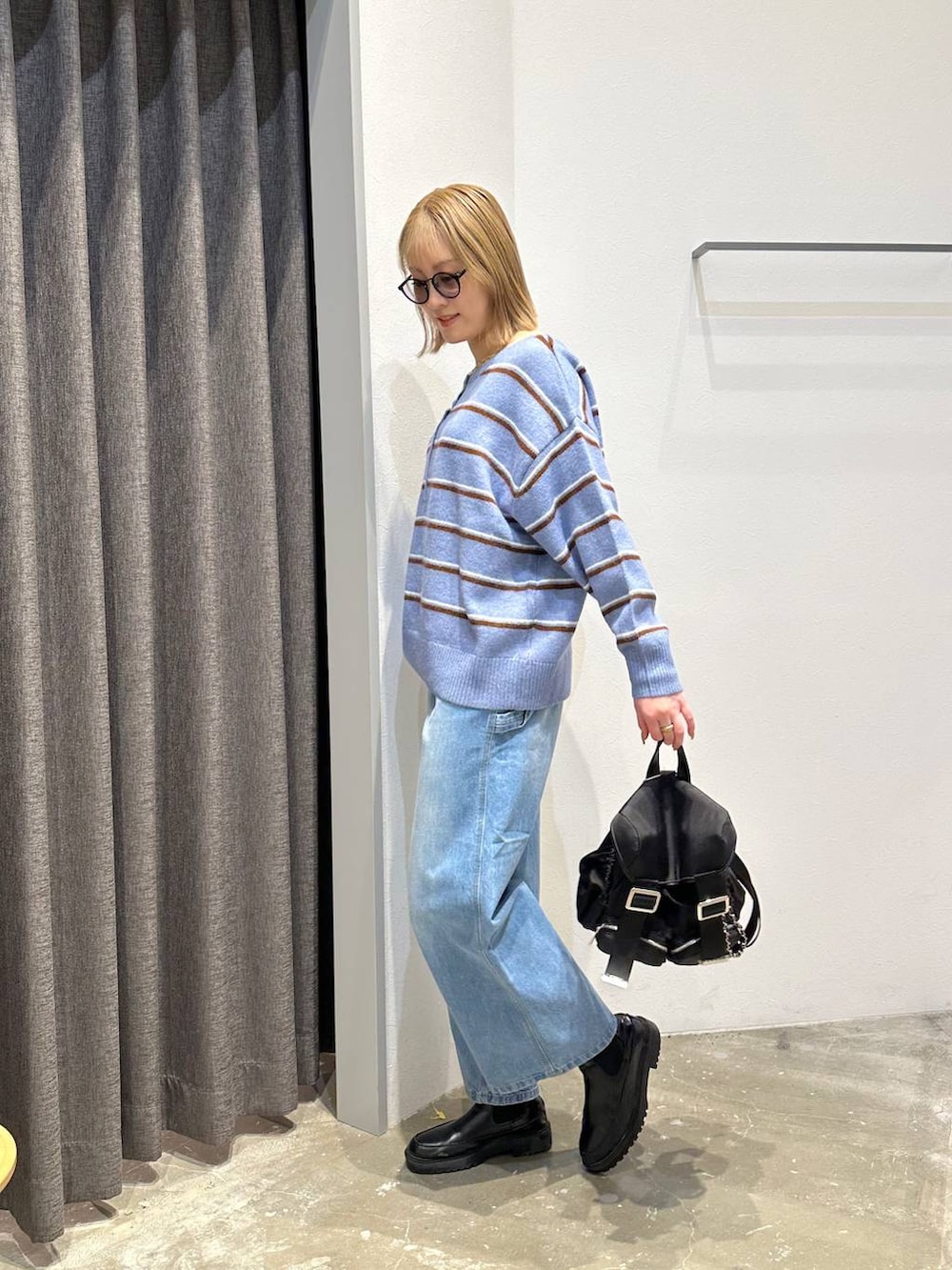 ブルー系のニット/セーター、ブルー系のデニムパンツ、ブラック系のバックパック/リュックを着用したレディースの冬コーディネートの2枚目の写真