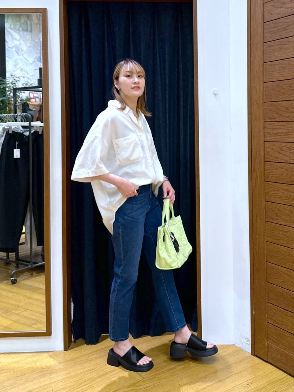 ブラック系のサンダル、ブルー系のデニムパンツ、グリーン系のトートバッグを着用したレディースの夏コーディネートの2枚目の写真