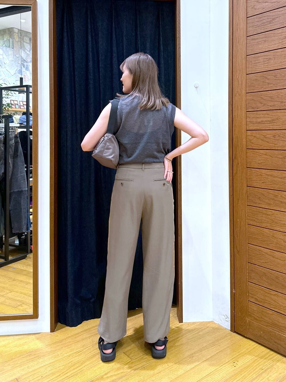 グリーン系のショルダーバッグ、ブラック系のベスト、ブラック系のサンダルを着用したレディースの秋コーディネートの3枚目の写真