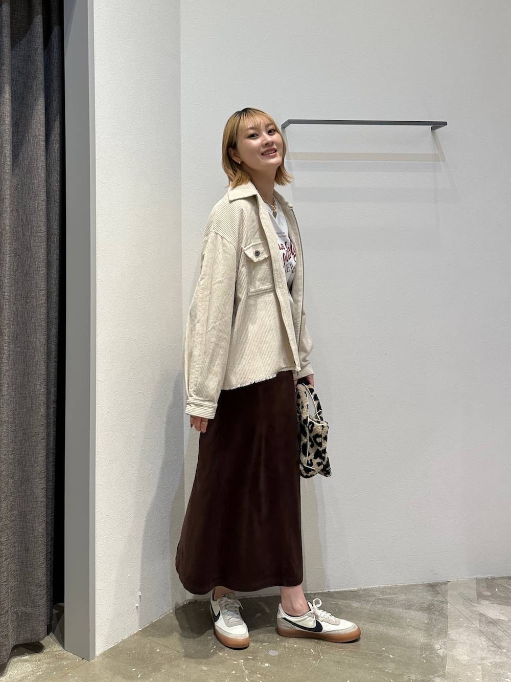 ブラウン系のスカート、ホワイト系のTシャツ/カットソー、ホワイト系のブルゾンを着用したレディースの秋コーディネートの2枚目の写真