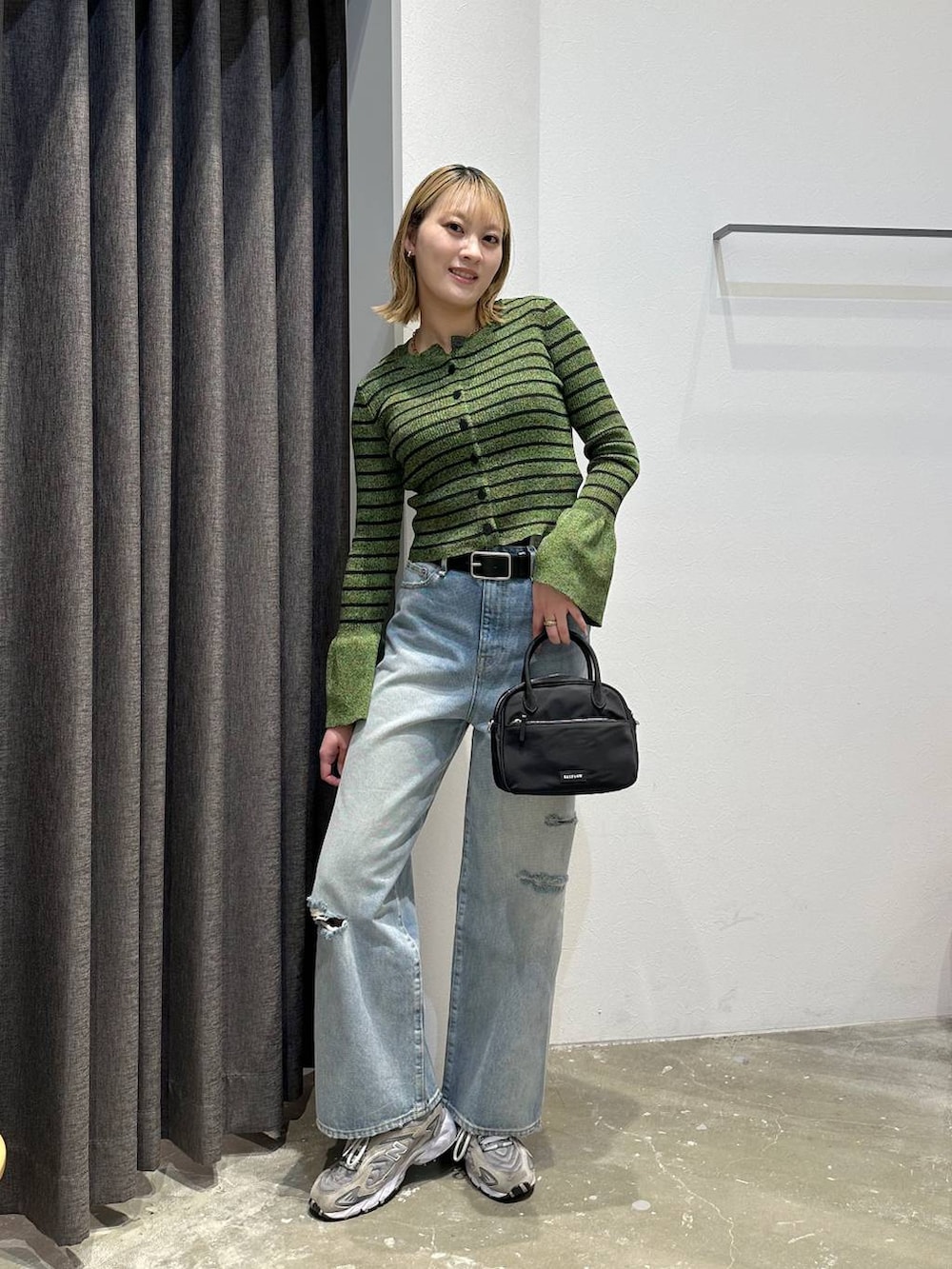 ブルー系のデニムパンツ、グリーン系のニット/セーター、ブラック系のベルトを着用したレディースの春コーディネートの2枚目の写真