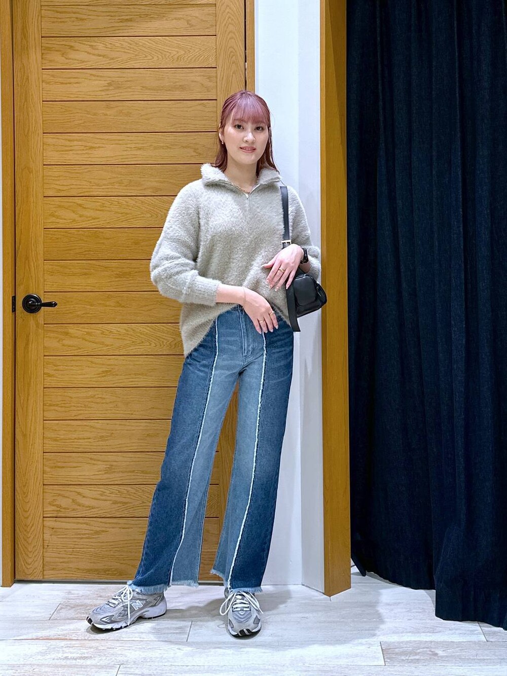 ブルー系のデニムパンツ、ブラック系のハンドバッグ、ベージュ系のニット/セーターを着用したレディースの秋コーディネートの4枚目の写真