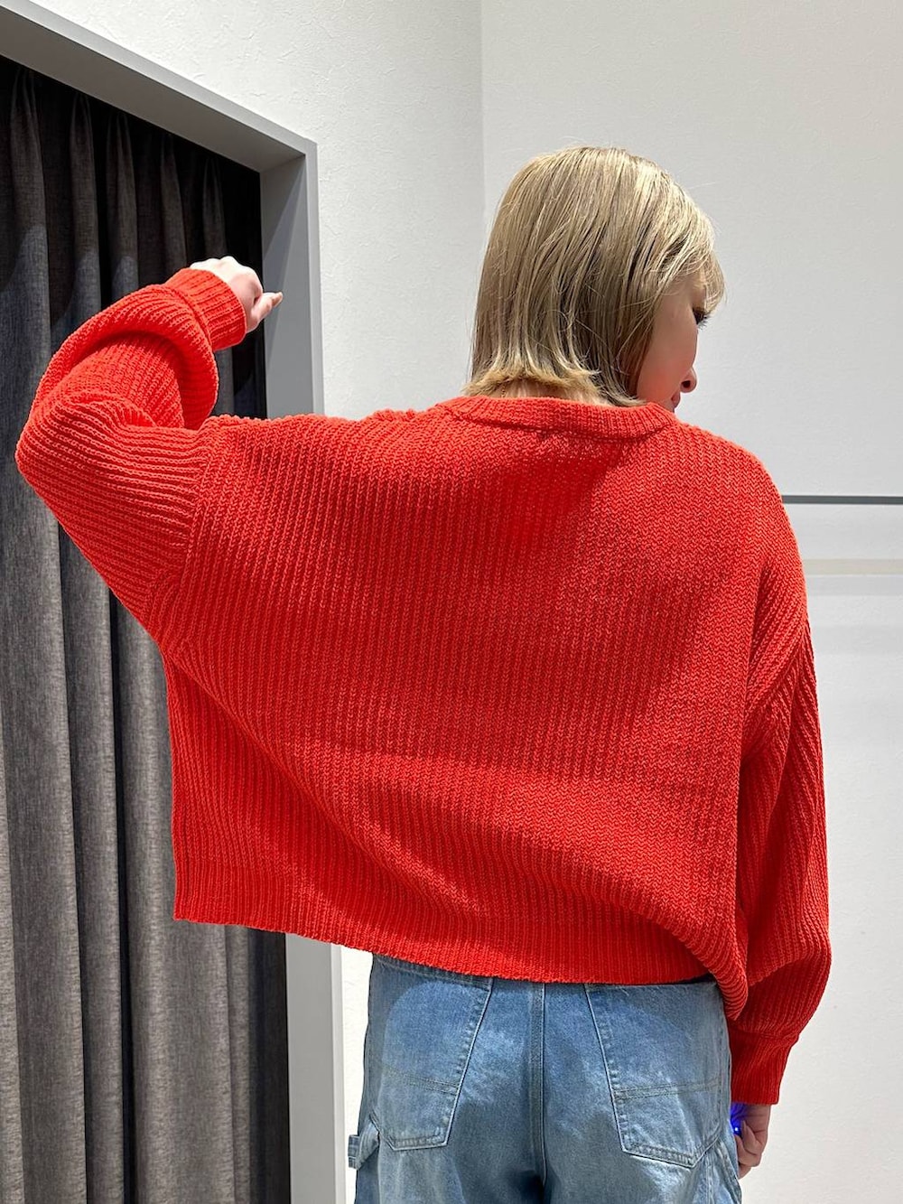 ブルー系のデニムパンツ、レッド系のニット/セーター、ブラック系のバックパック/リュックを着用したレディースの冬コーディネートの6枚目の写真