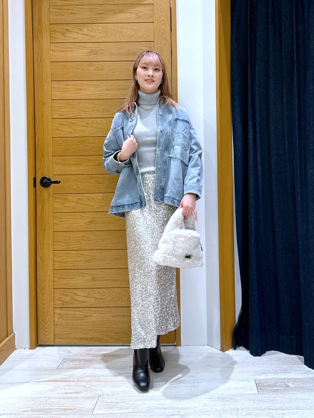 グレー系のニット/セーター、ブルー系のデニムジャケット、ブラック系のブーツを着用したレディースの秋コーディネートの4枚目の写真