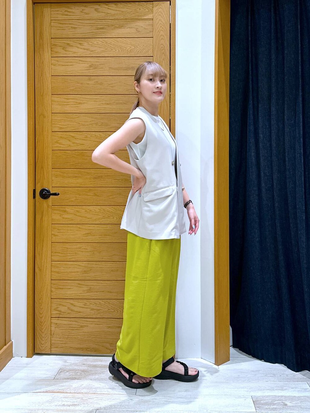 ホワイト系のTシャツ/カットソー、ベージュ系のベスト、ブラック系のサンダルを着用したレディースの夏コーディネートの2枚目の写真