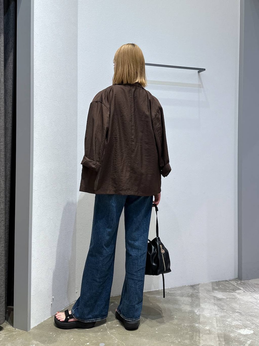 ブルー系のデニムパンツ、グレー系のTシャツ/カットソー、ブラック系のハンドバッグを着用したレディースの秋コーディネートの3枚目の写真