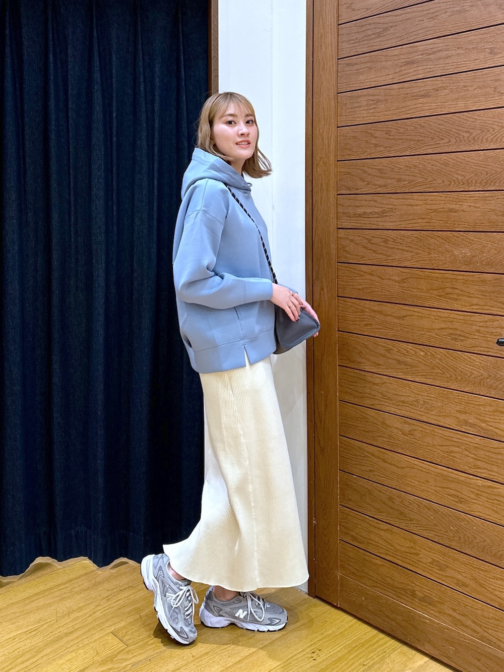 ブルー系のパーカー、グレー系のショルダーバッグ、ベージュ系のスカートを着用したレディースの春コーディネートの2枚目の写真