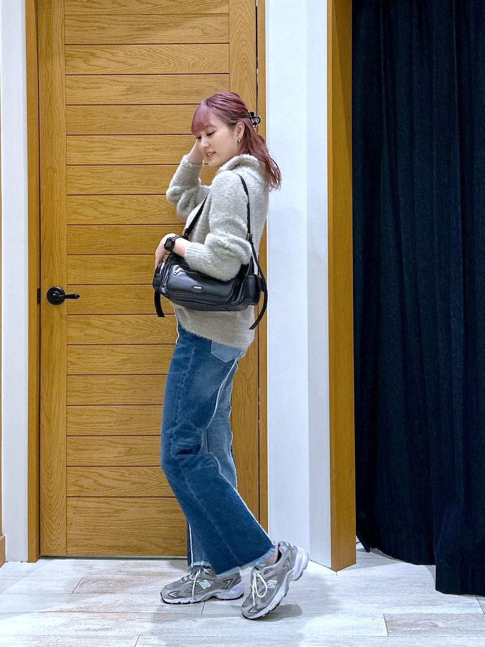 ブルー系のデニムパンツ、ブラック系のハンドバッグ、ベージュ系のニット/セーターを着用したレディースの秋コーディネートの2枚目の写真