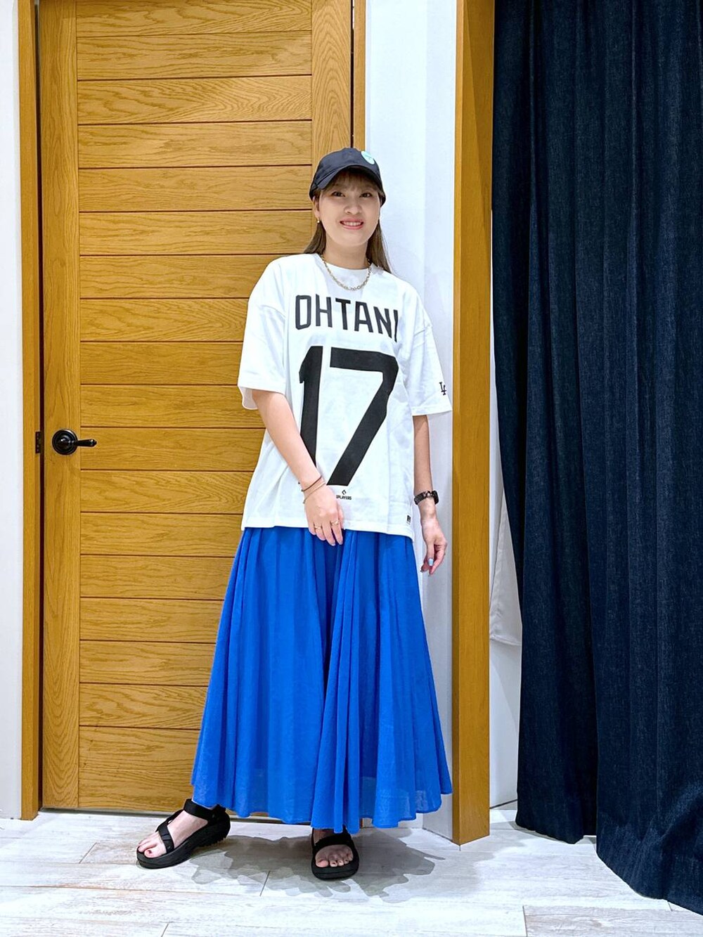 ブルー系のスカート、ブラック系のサンダル、ホワイト系のTシャツ/カットソーを着用したレディースの夏コーディネートの4枚目の写真