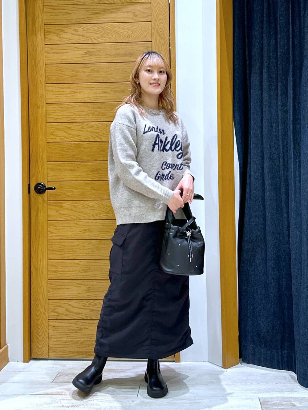 ブラック系のスカート、ブラック系のブーツ、ブラック系のショルダーバッグを着用したレディースの冬コーディネートの4枚目の写真