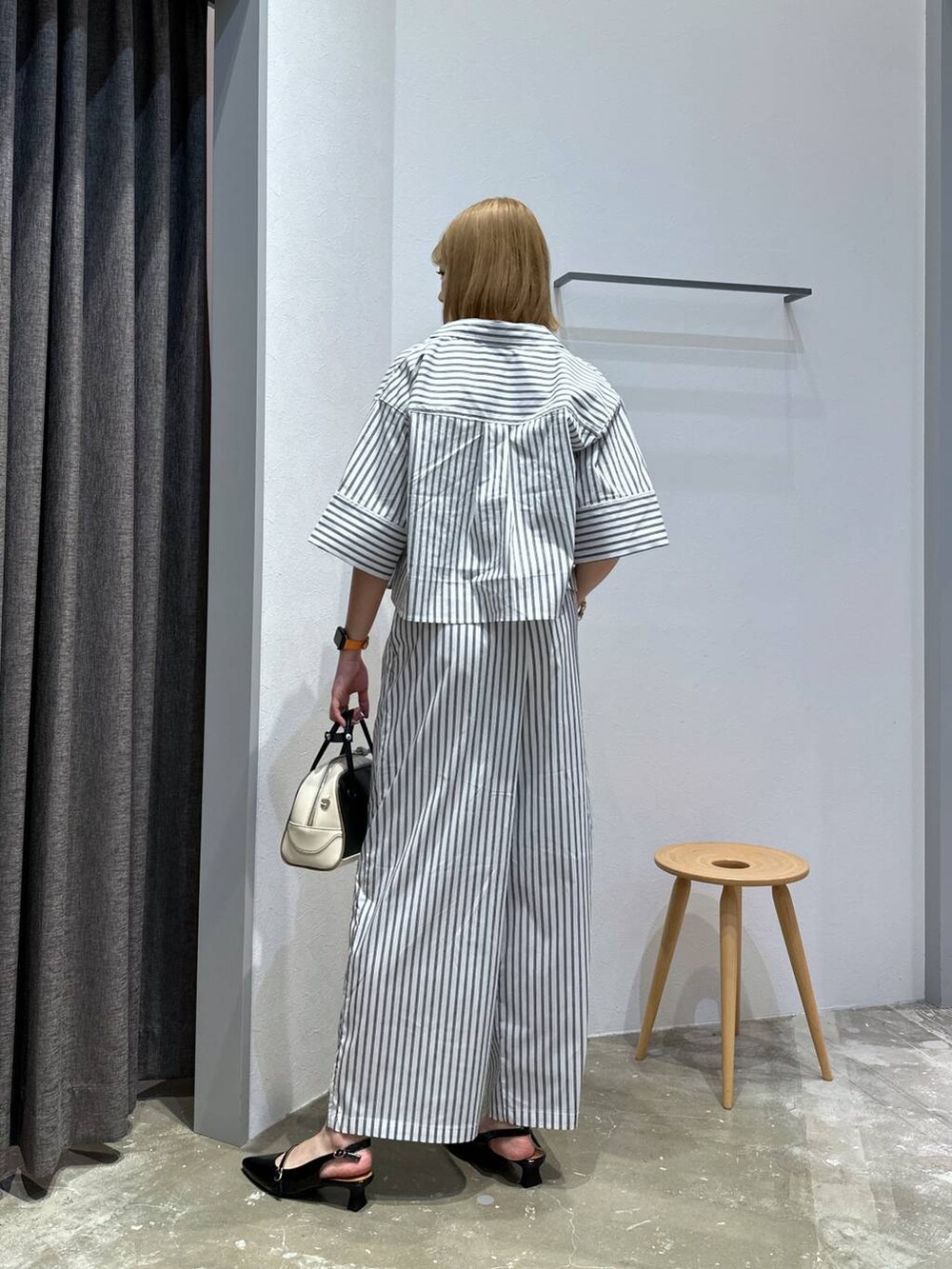 ブラック系のその他シューズ、ブラック系のハンドバッグ、ホワイト系のシャツ/ブラウスを着用したレディースの夏コーディネートの3枚目の写真