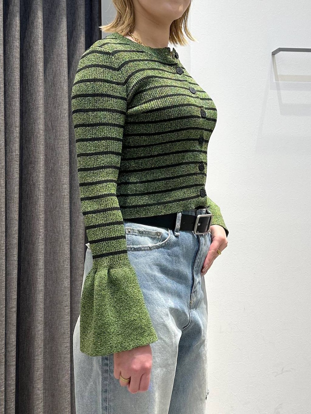 ブルー系のデニムパンツ、グリーン系のニット/セーター、ブラック系のベルトを着用したレディースの春コーディネートの5枚目の写真