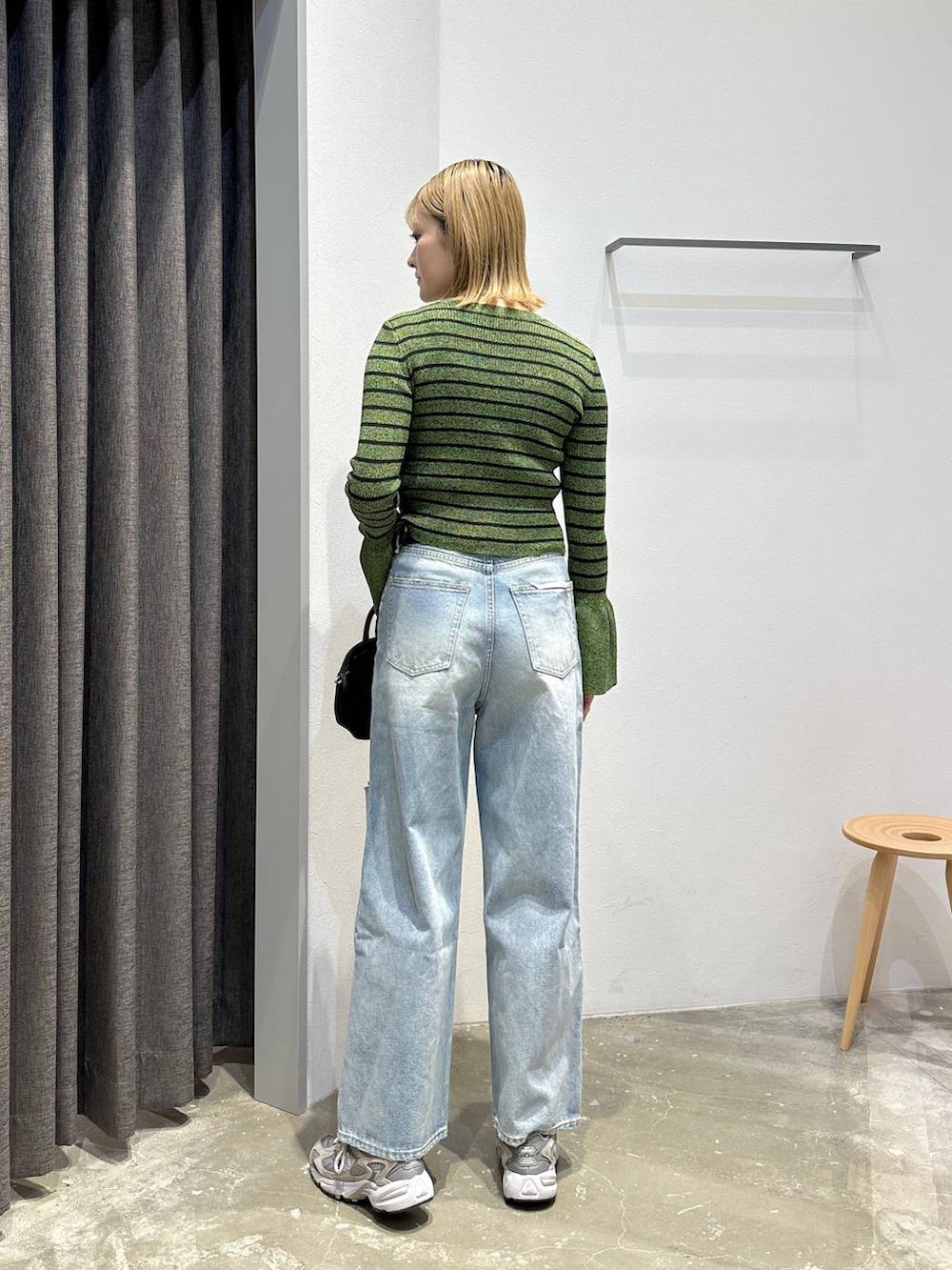 ブルー系のデニムパンツ、グリーン系のニット/セーター、ブラック系のベルトを着用したレディースの春コーディネートの4枚目の写真