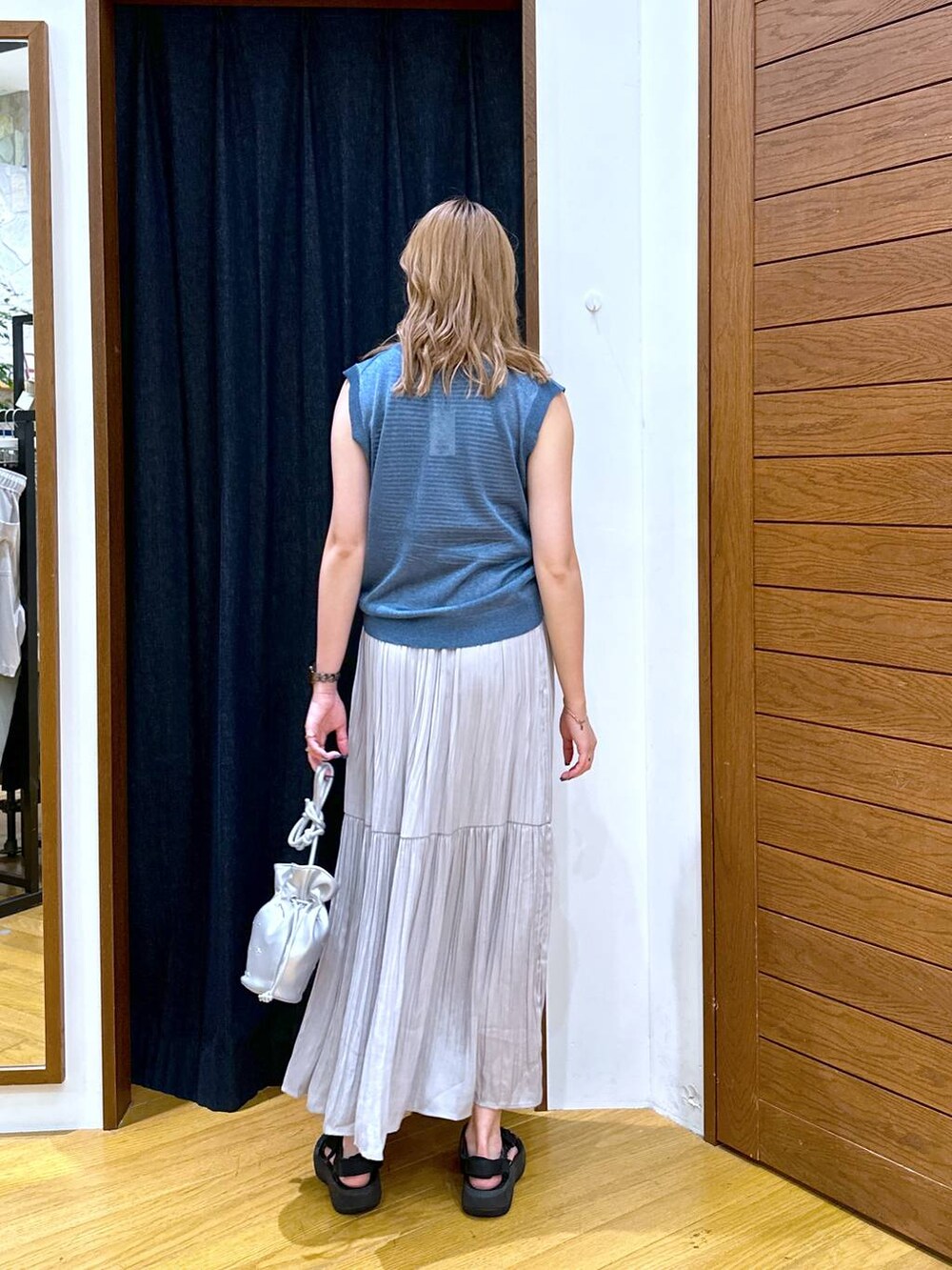 ブルー系のベスト、ブラック系のサンダル、グレー系のスカートを着用したレディースの夏コーディネートの3枚目の写真